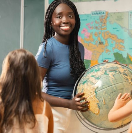 Sarah Julius in a classroom holding a globe