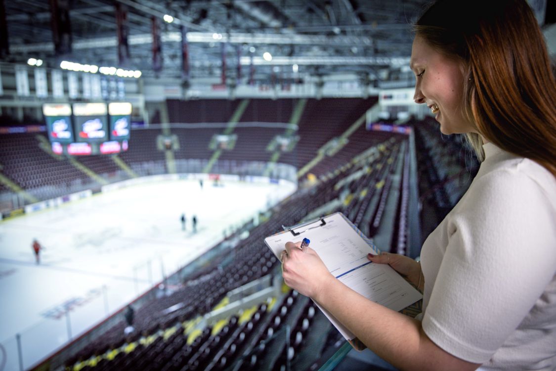 Woman with clipboard overlooking a hockey arena
