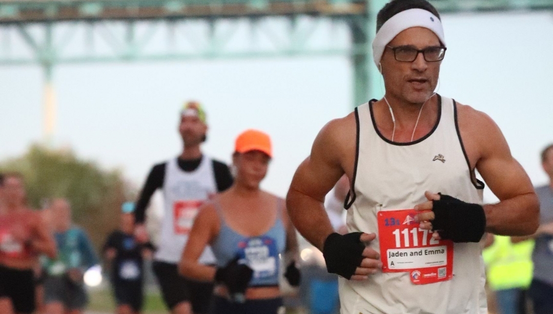 Chris Greig running in the Detroit half marathon with other runners behind him and the Ambassador Bridge in the background