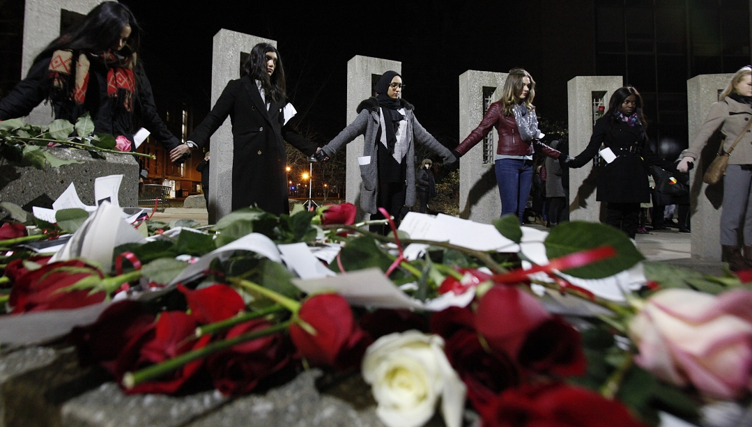 Students standing in front of the Memorial of Hope at UWindsor with roses in the foreground
