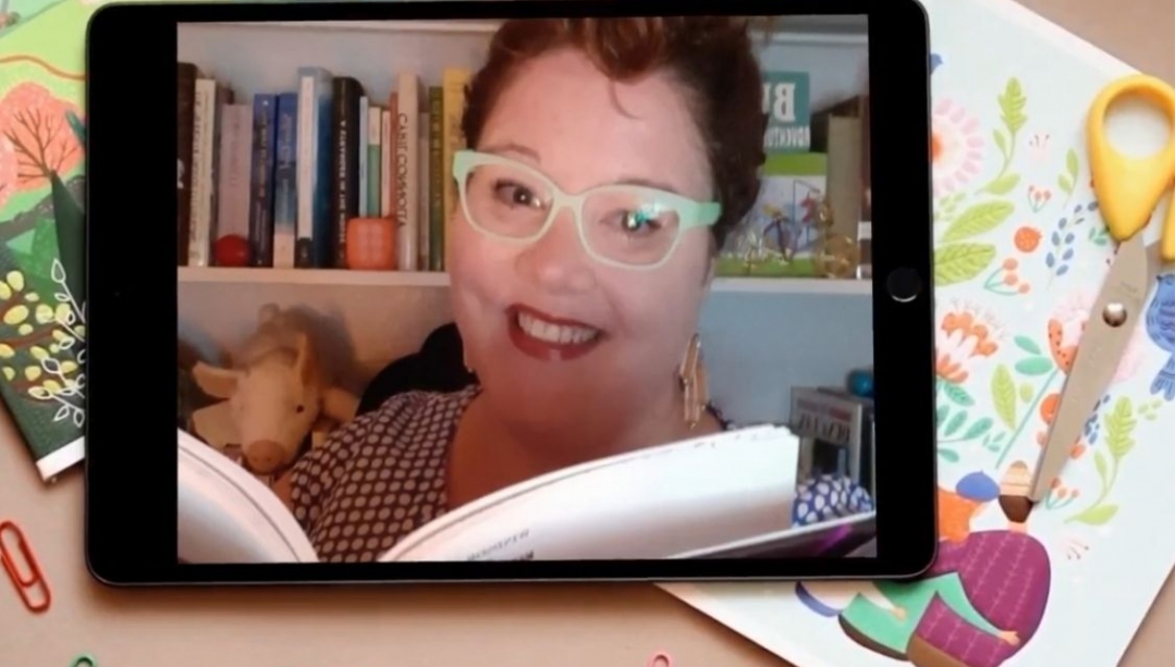 image of Kate Reynolds reading from a book and smiling superimposed on a tablet over some colourful drawings