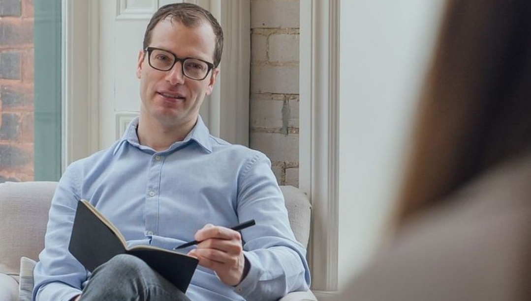 Alexander Daros seated holding a book