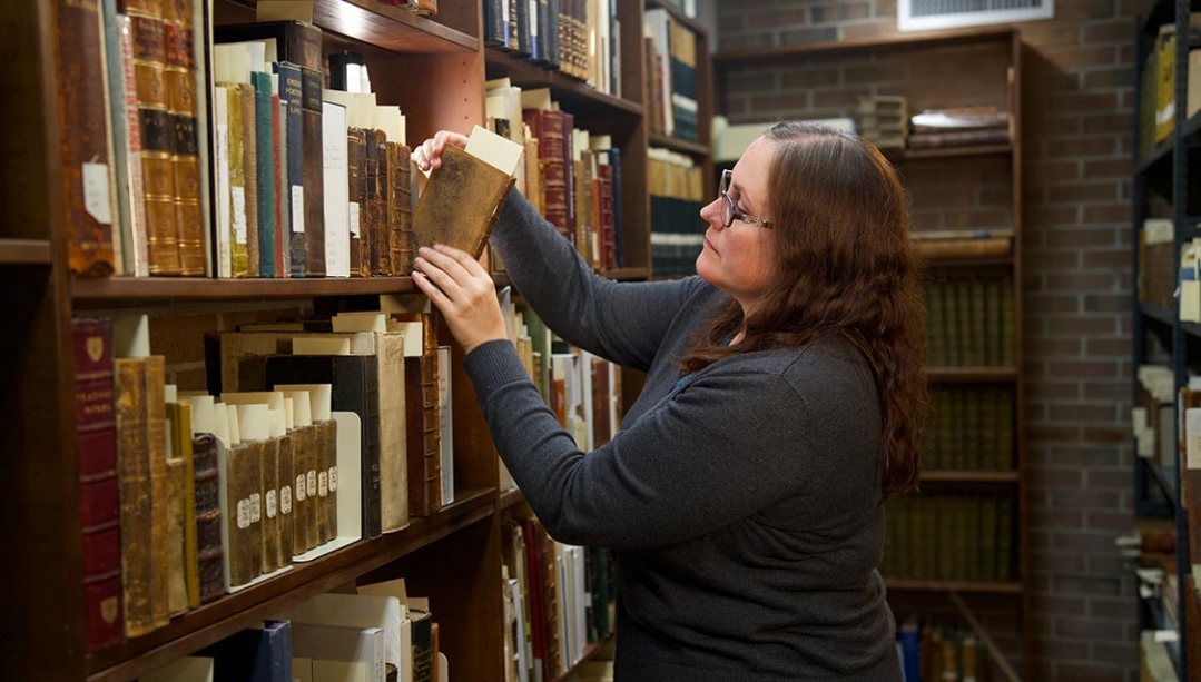 Archivist Dr. Sarah Glassford looking through books in Leddy Library's Archives and Special Collections.