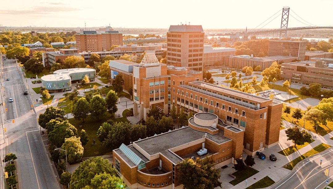Bird's eye view of Odette campus building with Ambassador bridge in background set against late afternoon sun