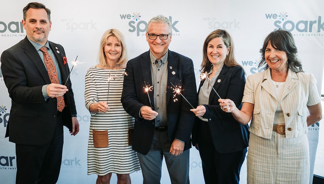 WE-Spark Health Institute members holding sparklers in celebration of renewed partnership