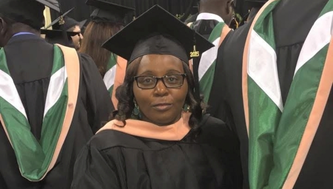 Corina Makore stands in a graduation cap and gown among other graduates