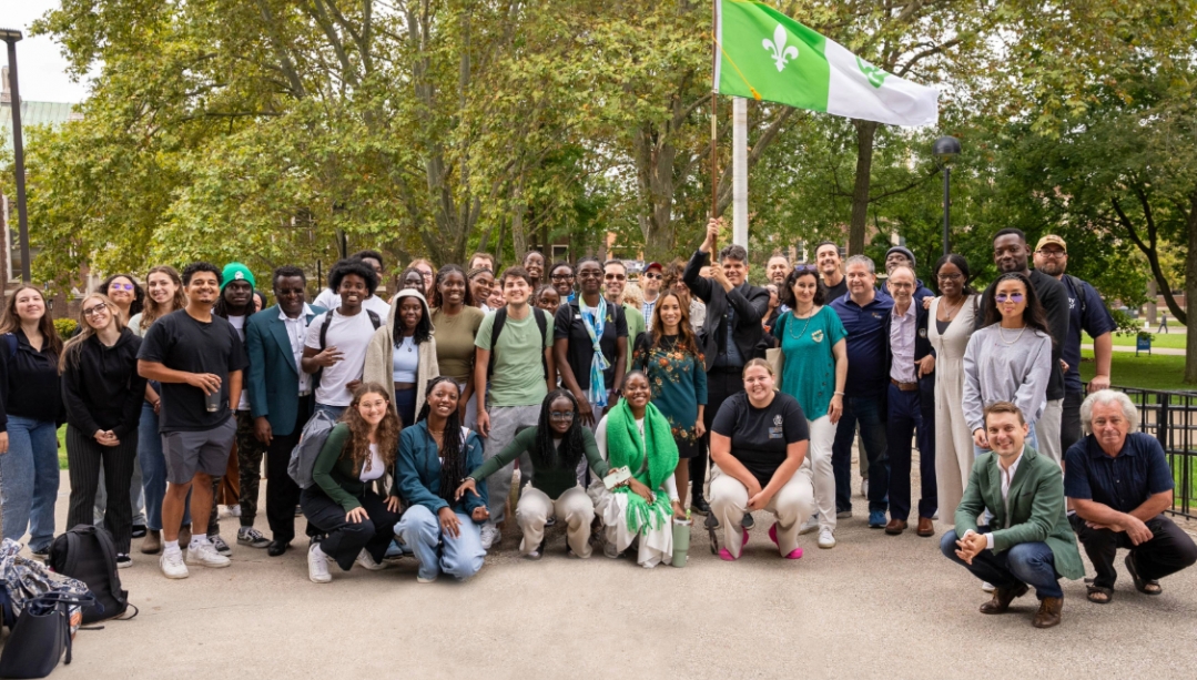 Students, faculty and staff stand outside for the Francophone flag raising