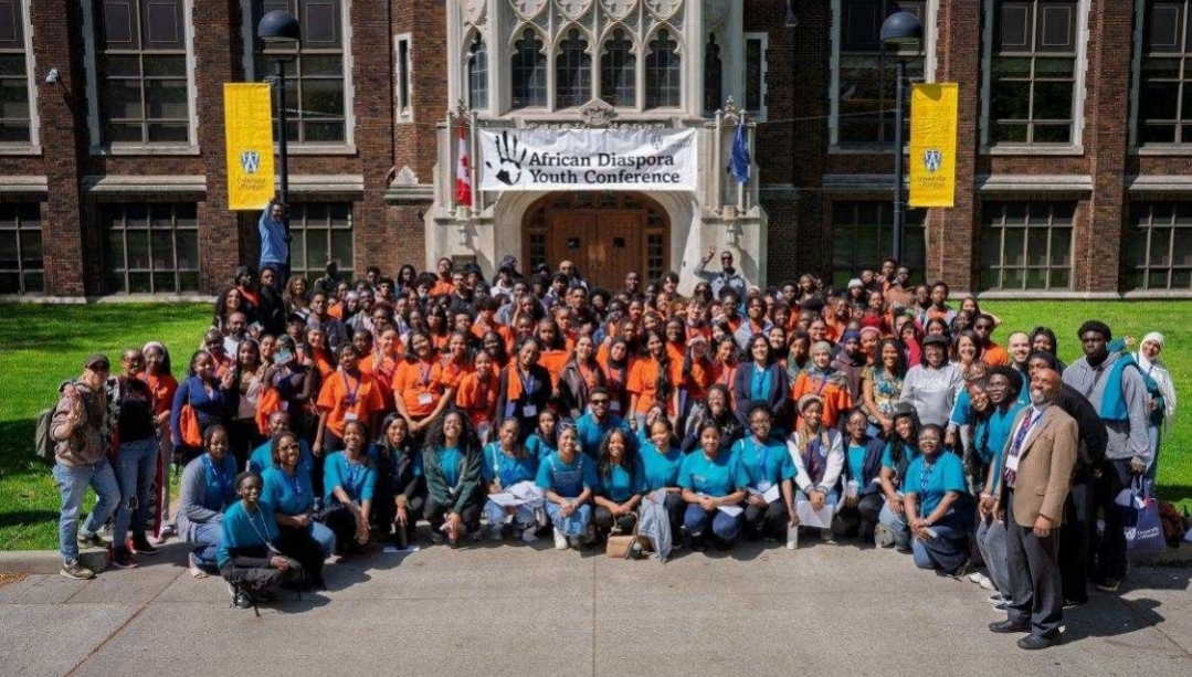 Group of students outside Dillon Hall with banner for African Diaspora Youth Conference