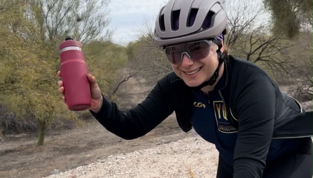 Kim Rocheleau holding a water bottle and wearing a cycling helmet