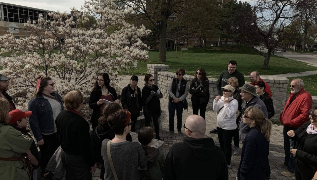 group of people on a tour outdoors in front of a flowering tree