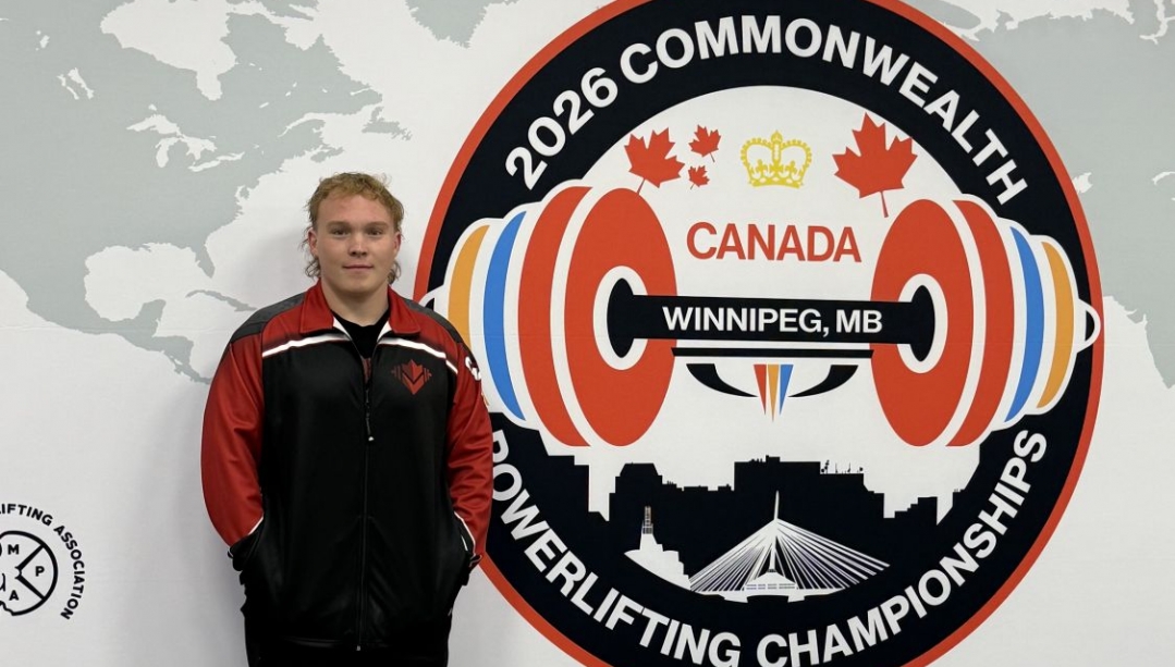 Ty Humphries in front of the logo for the 2026 Commonwealth Powerlifting Championships