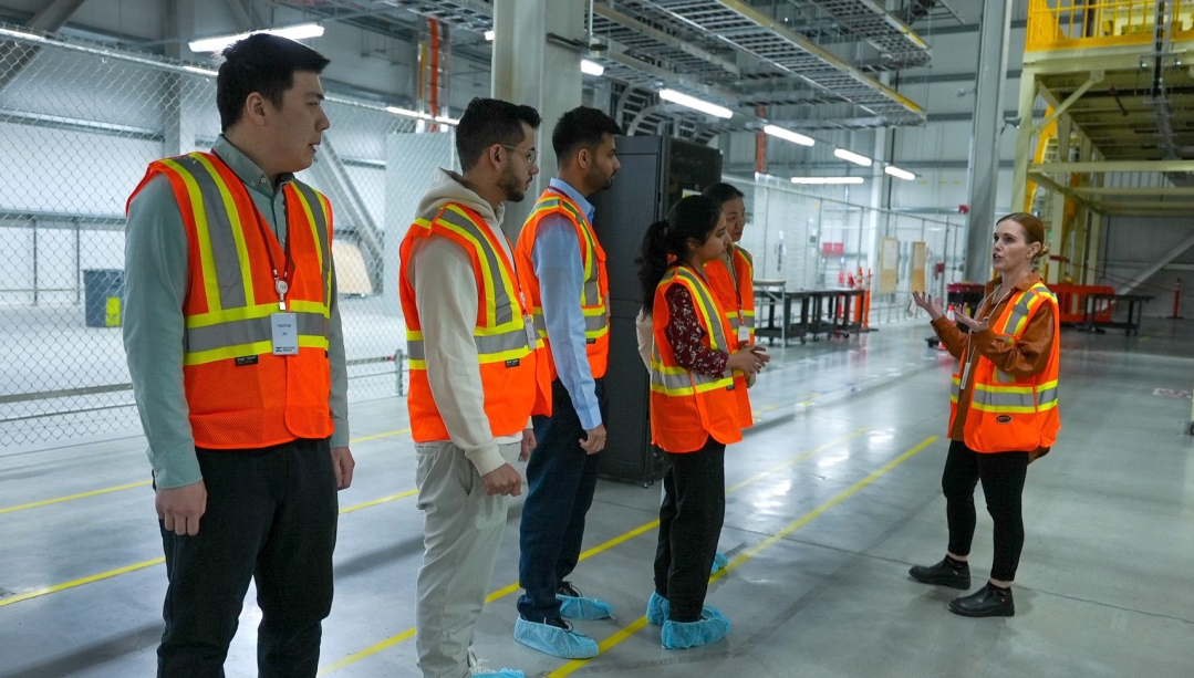 Students listen to employee during a guided tour of an industrial facility.