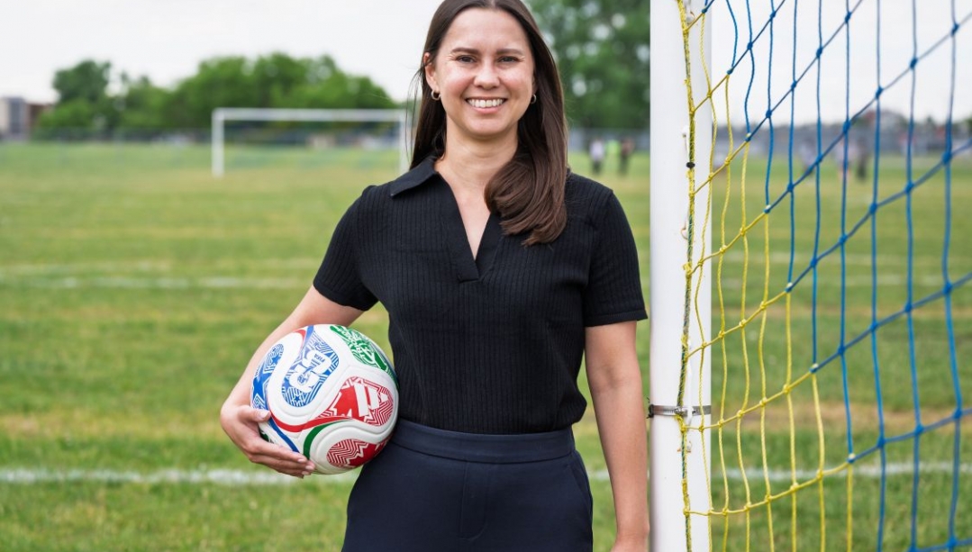 Kristen Morrison holding a soccer ball next to a soccer net