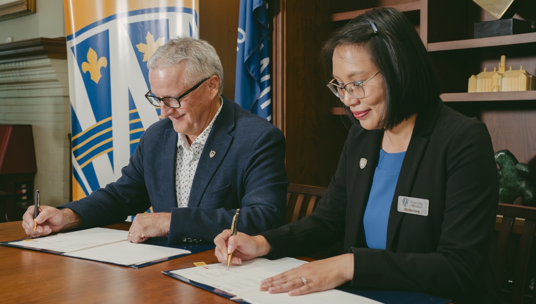 Former UWindsor President Robert Gordon and Alumni Association President Dorothy Leung sign memorandum of understanding documents.
