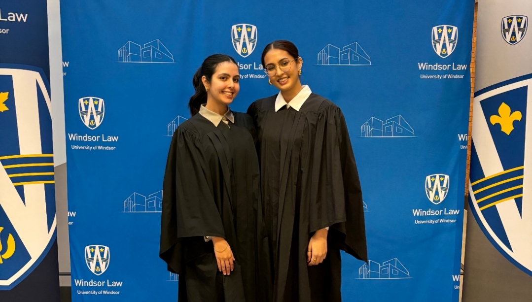 Jaskiran Braich stands with her classmate in front of a UWindsor sign.