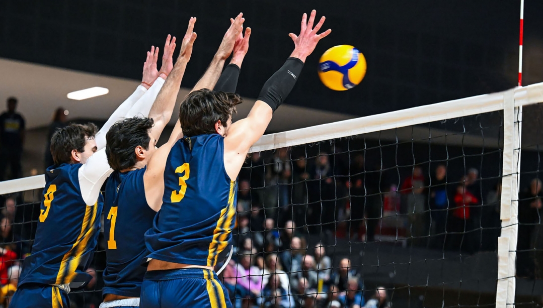 Lancers Men's Volleyball players jumping at the net for a spike block.