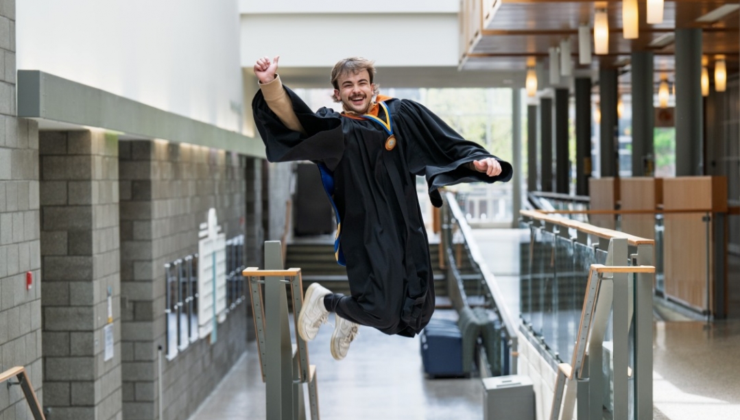 Ethan jumps for joy in his graduation gown