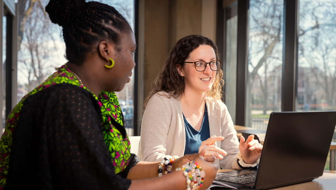 Two people take part in online meeting through laptop computer.
