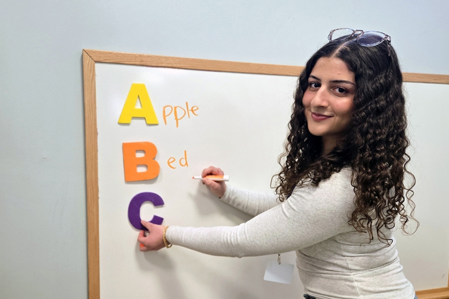 Photo of Michelle Eid at a white board writing the alphabet
