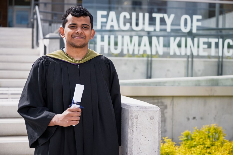 Aravind Manilal Valliyate in grad robe in front of Human Kinetics building