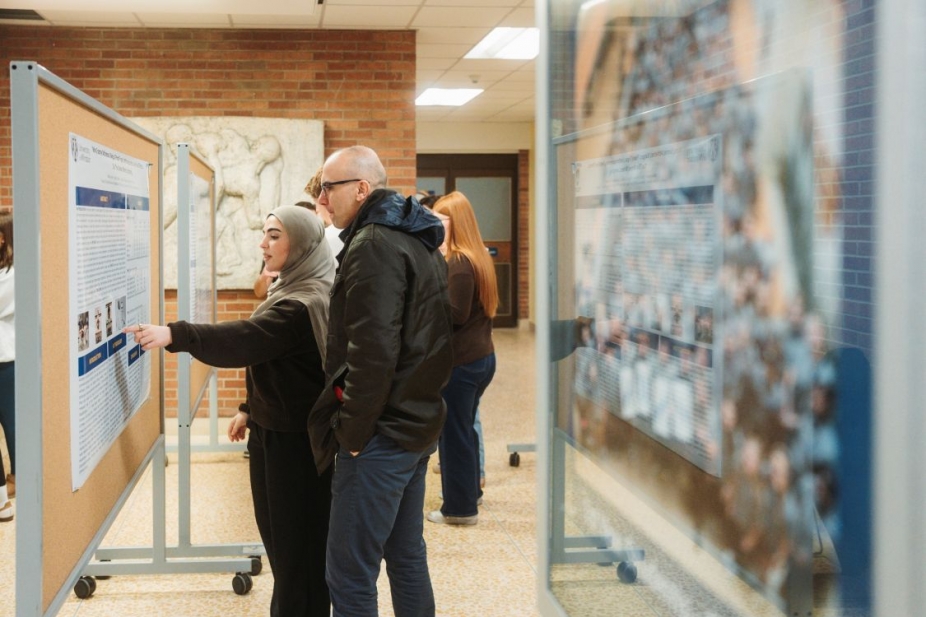 Two people look at a poster in a hallway