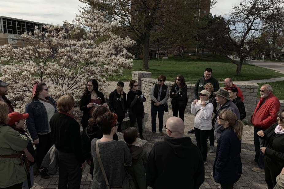 group of people on a tour outdoors in front of a flowering tree