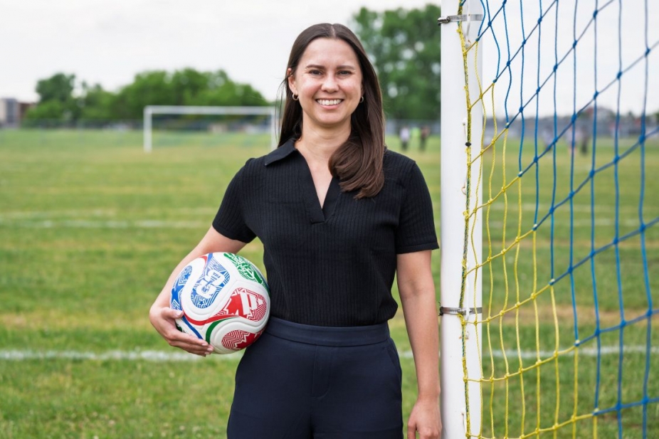 Kristen Morrison holding a soccer ball next to a soccer net