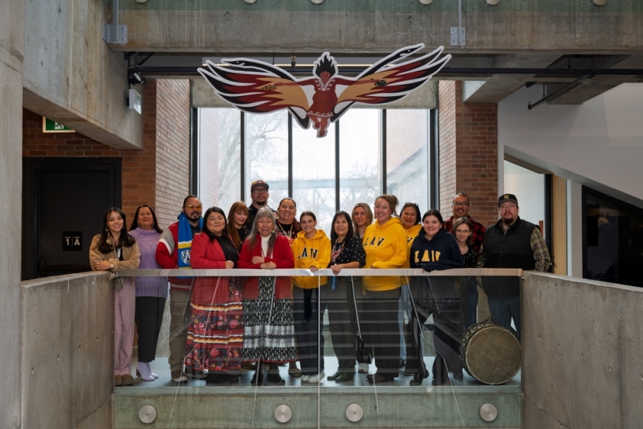A group of law faculty and staff stand beneath the Sky Woman art installation