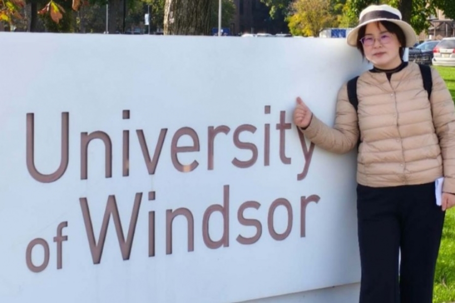 Min Fan next to University of Windsor sign