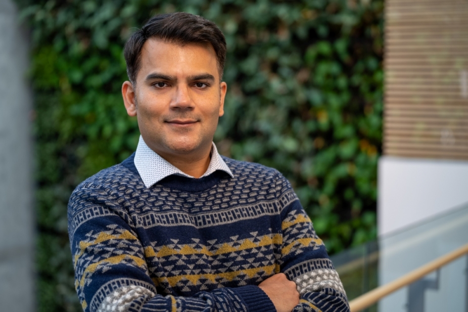 Dr. Noeman Mirza stands in front of a living wall in the faculty of nursing