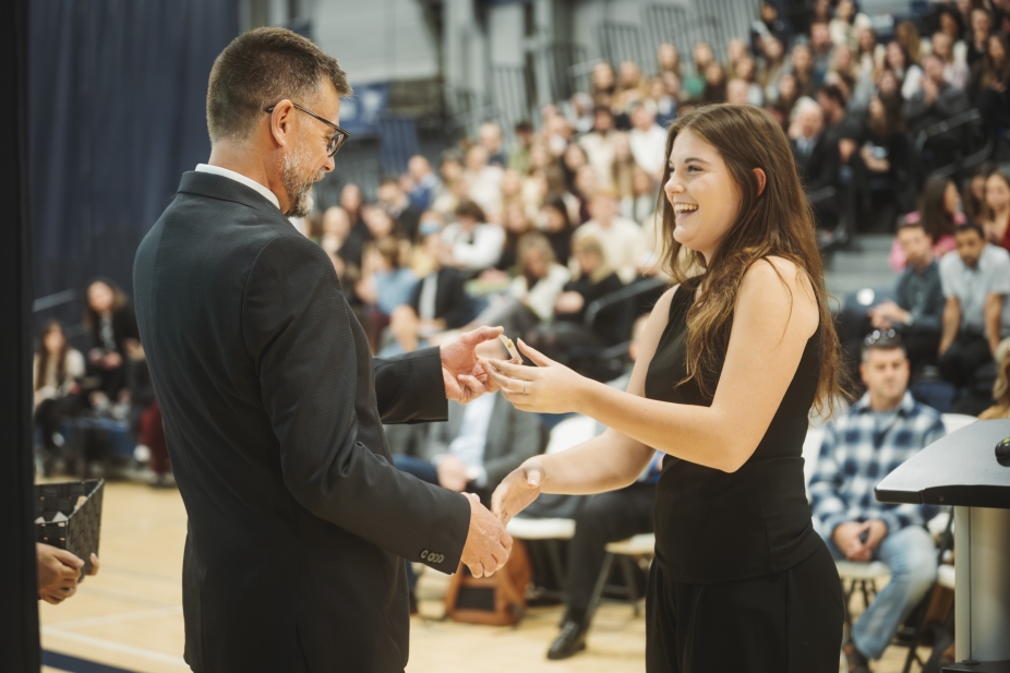 Ken Montgomery hands a student a pin