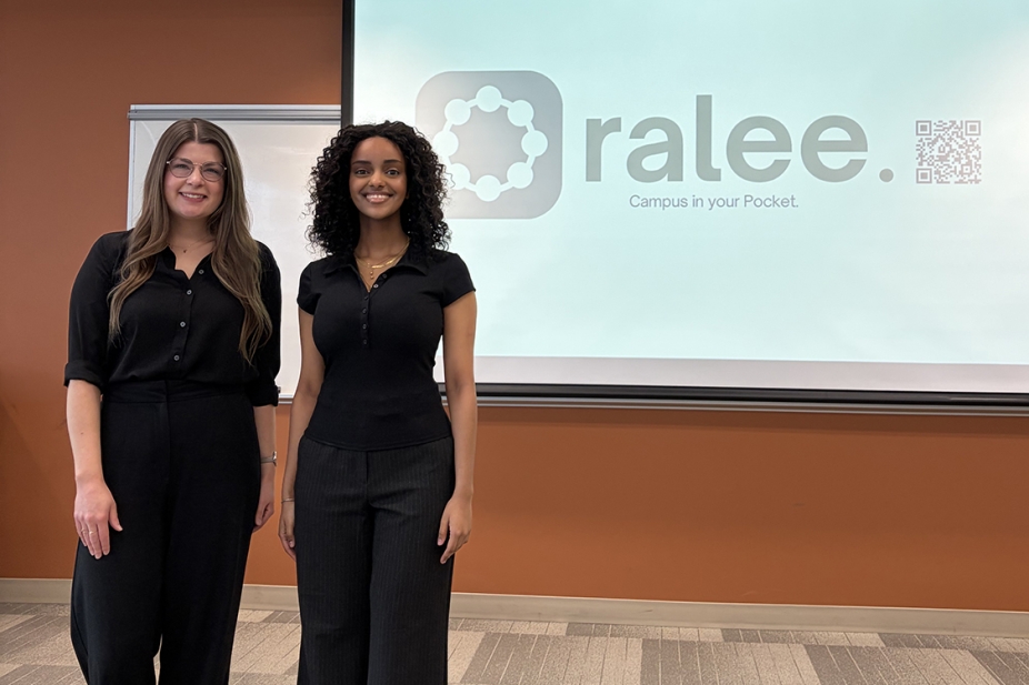 photo of Sydney Thompson and Kalkidan Wubshet standing at the head of boardroom