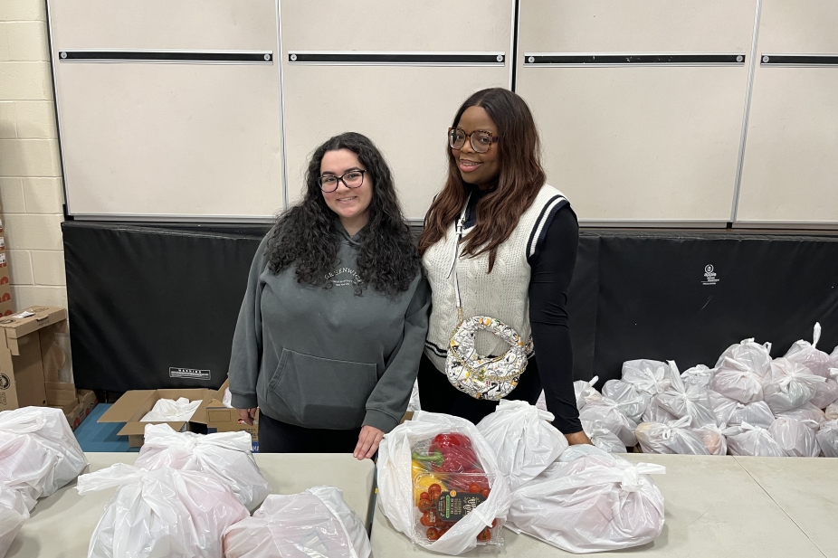 two students standing behind bags of produce