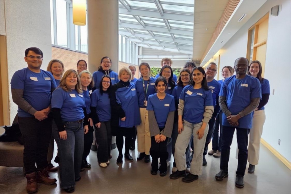 A group of nursing faculty and students stand in the atrium area of the nursing building.
