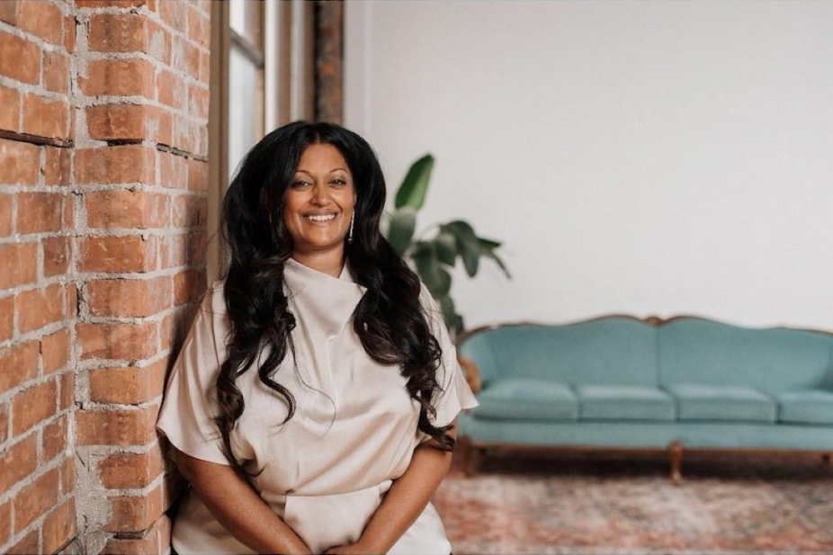 Dr Shanthi Senthe stands beside a brick wall in a stylish room