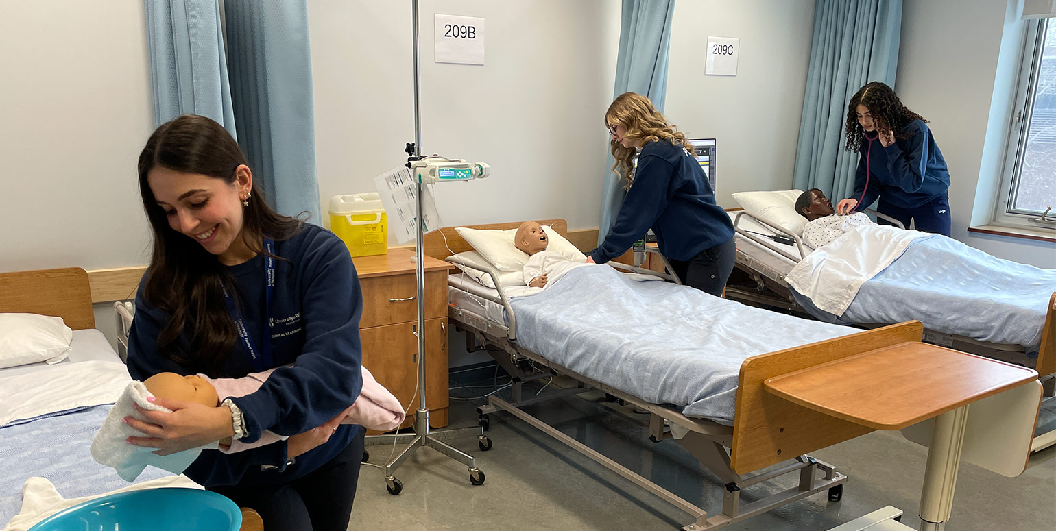 Nursing students practicing their skills on a mannequin in a simulation lab