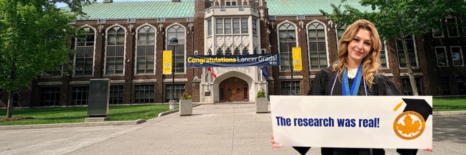 Student standing in front of Dillon Hall with sign saying the research was real!