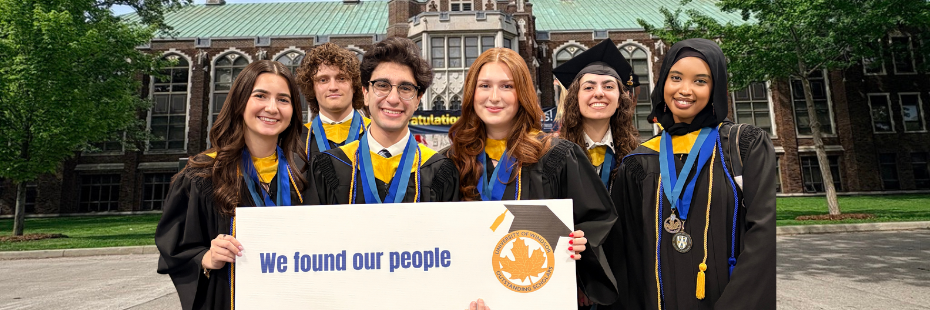 Students standing in front of Dillon Hall - holding a sign saying we found our people
