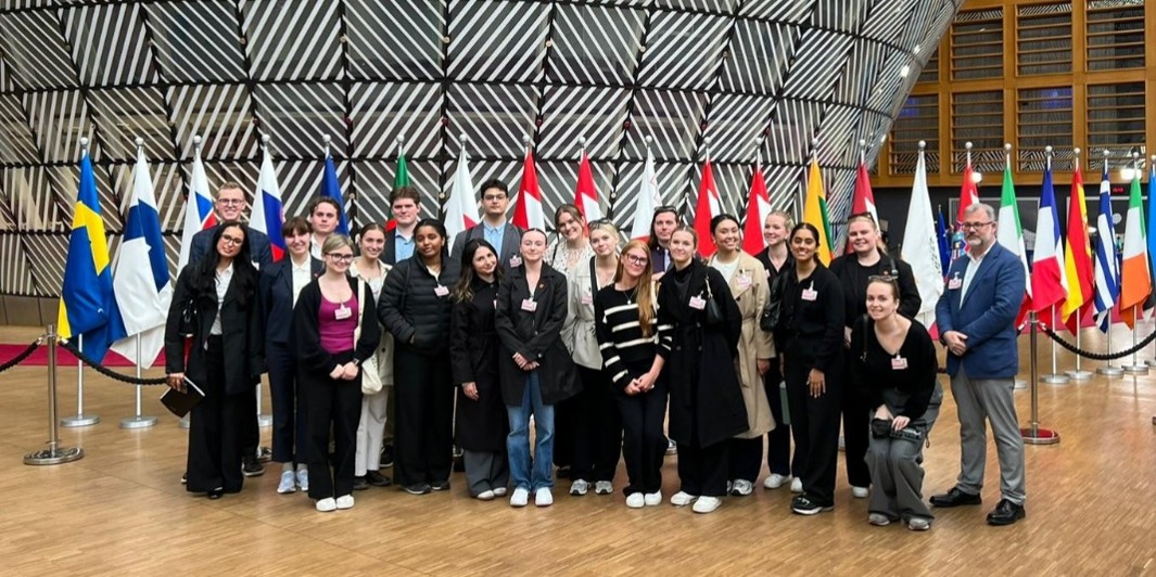 A group of students standing front of flags at the European Council