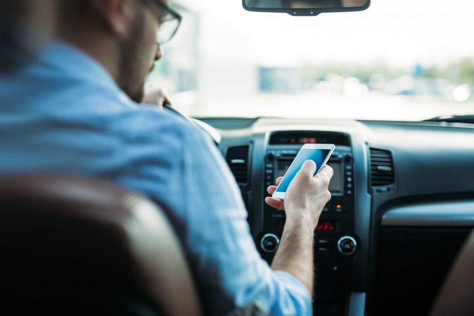 A man looks at his phone while driving.