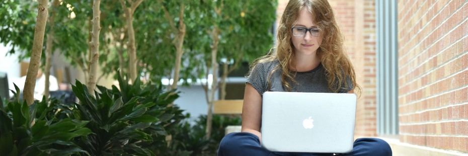 Student sitting on the floor, working on their laptop
