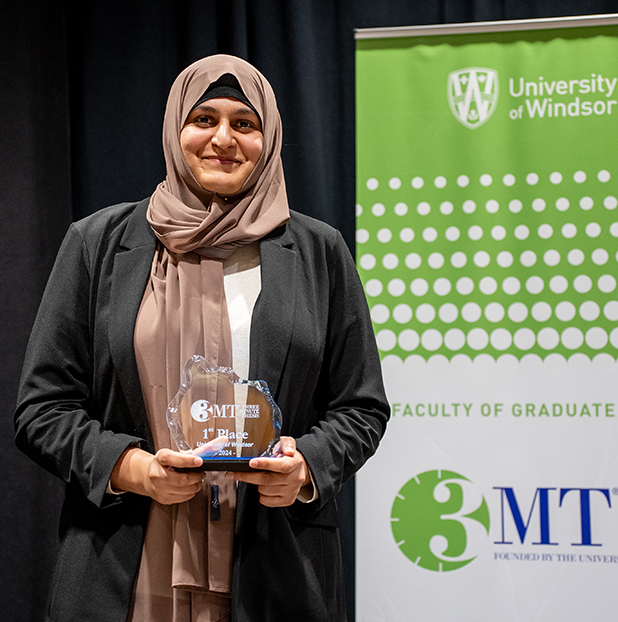 student holding three minute thesis trophy