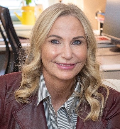 Headshot of woman smiling, in an office setting.