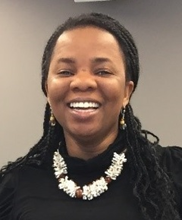 Headshot of woman smiling, in front of a grey background.