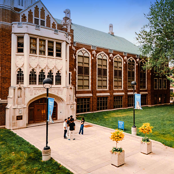 High and side angle view of Dillon Hall with sudents standing along front walkway