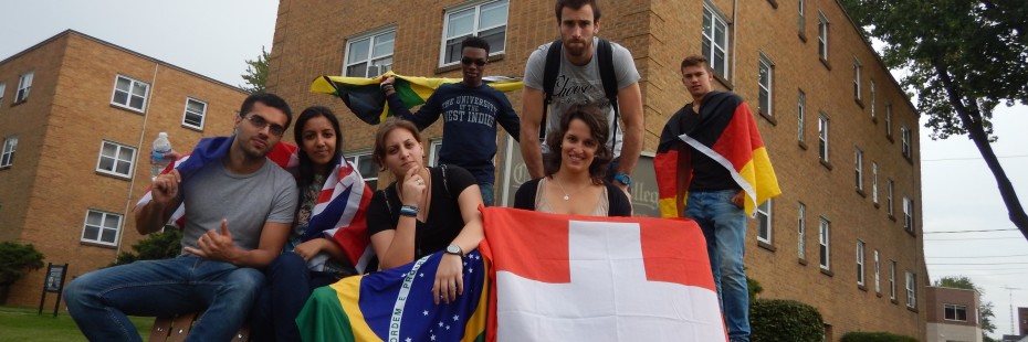 Incoming exchange students pose outside of residence building with flags