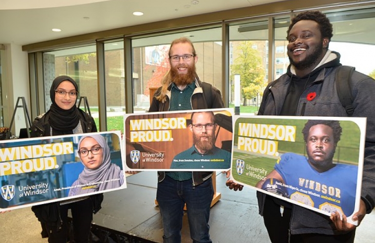 UWindsor students Amal Siddiqui, Max Arvidsson, and David Adelaja pose with mock-ups of billboards bearing their images as part of the Windsor Proud campaign