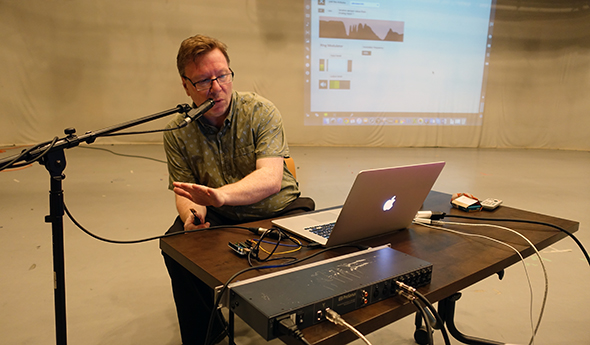 Dr Brent Lee in front of a computer talking into a microphone