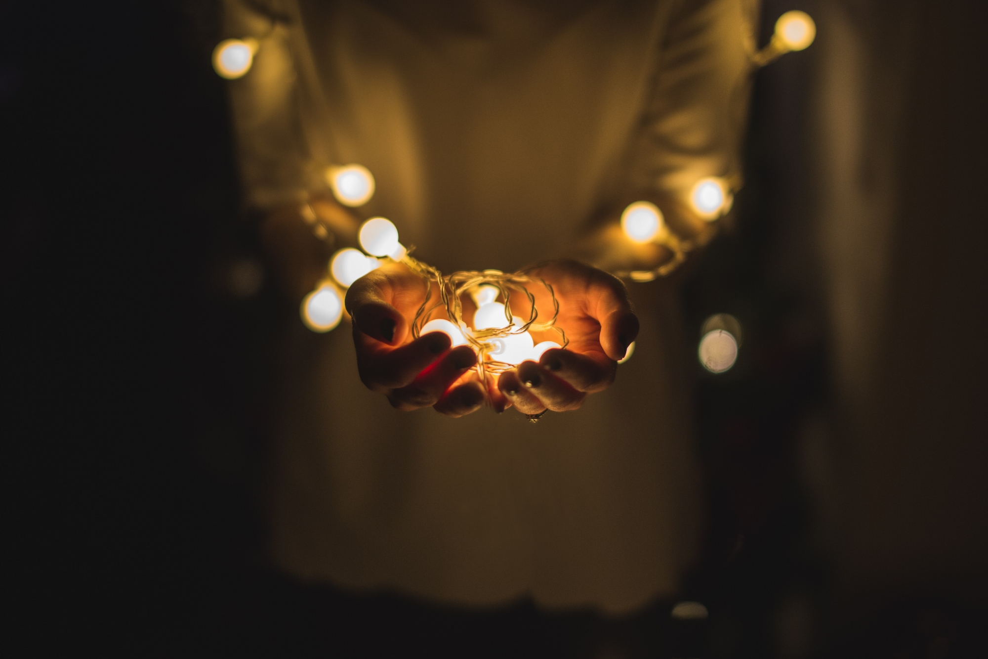 Dark image of hands holding twinkle lights