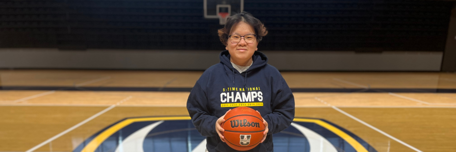 Alyssa holding a basketball standing in the middle of the Toldo Lancer Centre basketball court